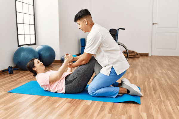 A physical therapist using a yoga pose with a client, demonstrating the benefits of combining physical therapy and yoga therapy.