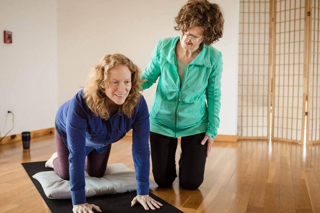Two students in Breathing Deeply's yoga therapy program practicing how to use asana with clients, just one way to use yoga in social work