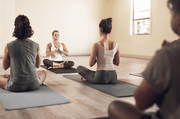 A yoga teacher leading students in a group, demonstrating a major difference between yoga teacher and yoga therapist practices.