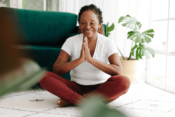 A woman smiling and practicing Ayurvedic yoga therapy for physical, mental, and emotional health