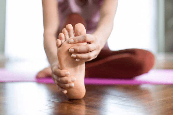 A woman stretching out her leg and foot, an example of toe yoga physical therapy