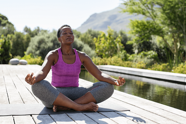 A Black woman sitting in lotus position, representing an example of an eligible student for our scholarship program to reduce the cost to become a yoga therapist