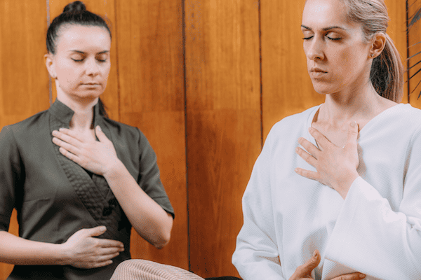 A woman doing breathing exercises with the help of a psychotherapist with yoga training