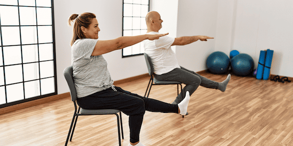 A yoga therapist who has completed yoga for cancer training helps a client to stretch