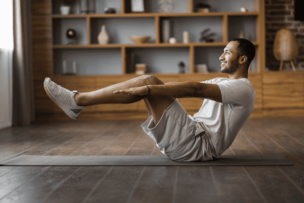 A Black man practicing a core strengthening pose as part of yoga or Pilates for back pain