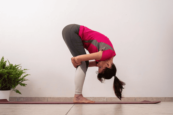 A woman practicing a forward bend, demonstrating one possible reason why yoga may make you nauseous.