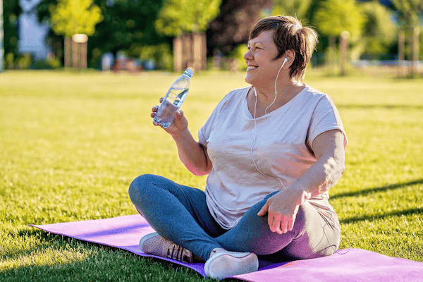If you practice yoga for menopause hot flashes, remember to hydrate, as this woman demonstrates by keeping a water bottle handy during yoga