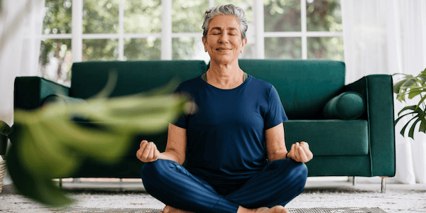 A calm-looking woman cross-legged on the floor practicing yoga for menopause hot flashes